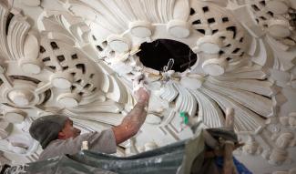 Artisan staffeur restaurant une rosace décorative au plafond du musée de la Résistance et de la Déportation de l’Aisne