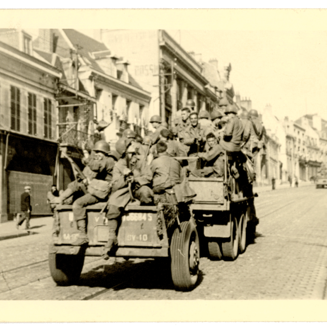 Soldats américains remontant la rue d’Isle à Saint-Quentin à bord d’un véhicule militaire en septembre 1944