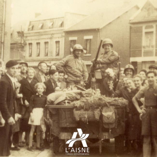 Photographie d’archive montrant une Jeep militaire américaine entourée d’habitants lors de la Libération de l’Aisne en 1944.