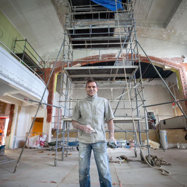 Artisan staffeur intervenant sur les décors du plafond du musée de la Résistance et de la Déportation de l’Aisne au pied de l’échafaudage de restauration