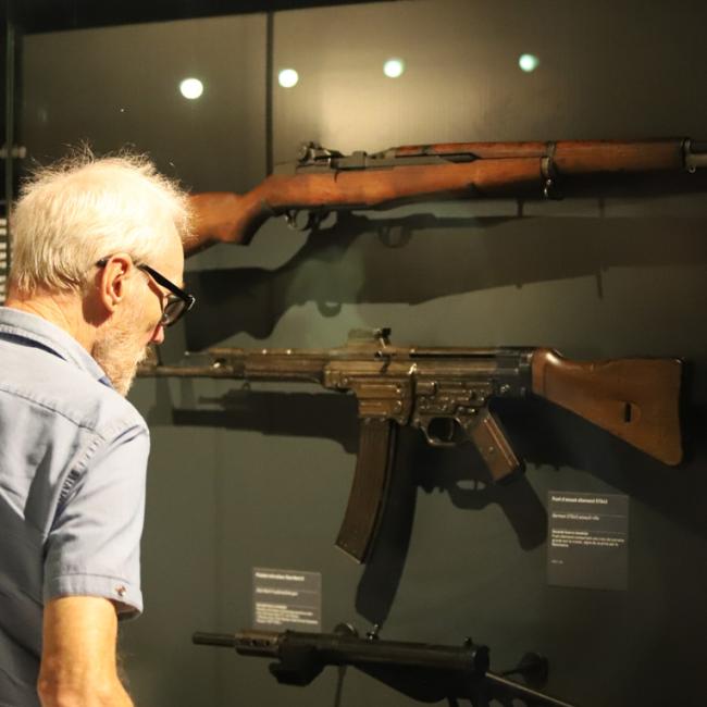 Visiteur observant des armes, documents et témoignages présentés dans le parcours de l’exposition permanente du Musée de la Résistance et de la Déportation de l’Aisne